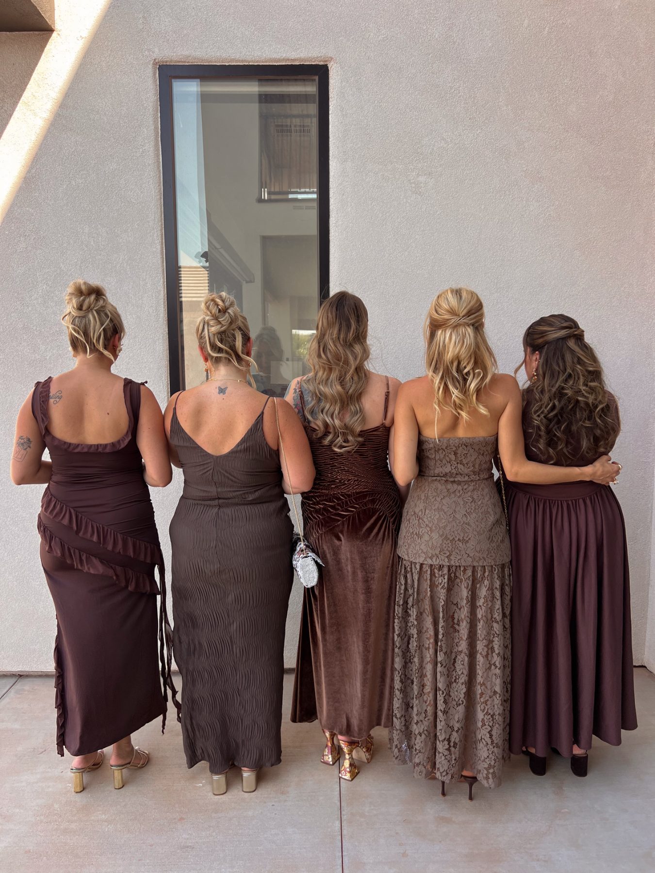 Bridal party in brown dresses, styled hair photographed from behind